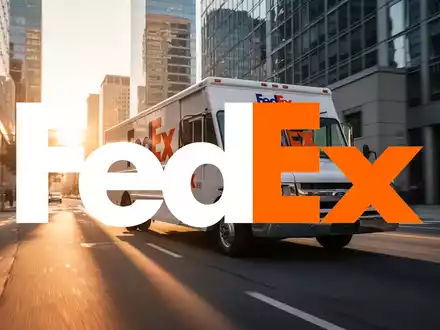Ein FedEx-Lieferwagen fährt auf einer Stadtstraße bei Sonnenuntergang, mit starkem Fokus auf die Dynamik der Logistik. - Foto: über boerse-global.de