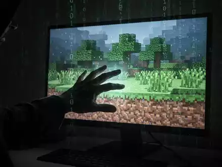 A shadowy hand reaching for a glowing, pixelated Minecraft world on a screen, symbolizing a cyber threat to the gaming community. - Foto: über boerse-global.de