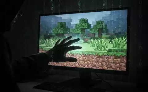 A shadowy hand reaching for a glowing, pixelated Minecraft world on a screen, symbolizing a cyber threat to the gaming community. - Foto: über boerse-global.de