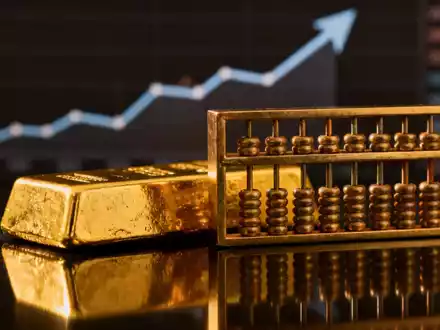 Ein glänzender Goldbarren neben einem traditionellen chinesischen Abakus, mit einem verschwommenen Finanzchart im Hintergrund. - Foto: über boerse-global.de