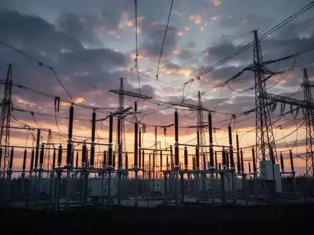 Eine Umspannstation mit Stromleitungen bei Sonnenuntergang, symbolisch für die Energieinfrastruktur und deren Regulierung. - Foto: über boerse-global.de