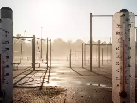Ein verlassener, sonnenüberfluteter Outdoor-Fitnessbereich oder Sportplatz mit Flimmern über dem Boden, das Hitze andeutet. - Foto: über boerse-global.de