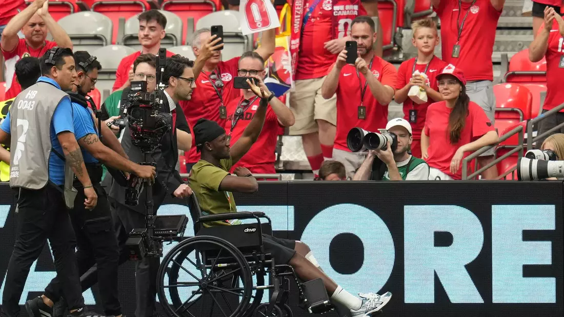 Im Rollstuhl: Koné wird im Stadion begrüßt. - Bild: Abbie Parr/AP/dpa