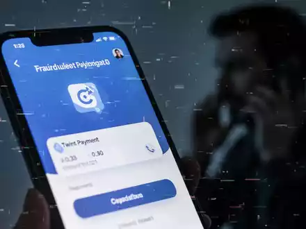Ein Smartphone-Bildschirm zeigt eine betrügerische Twint-App-Oberfläche mit Glitch-Effekten. Im Hintergrund eine Person, die telefoniert. - Foto: über boerse-global.de