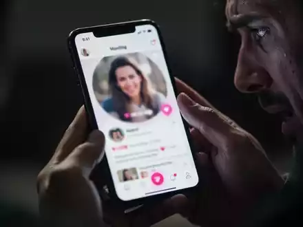 Nahaufnahme eines Smartphones mit einer Dating-App, das von besorgten Händen gehalten wird, im Hintergrund verschwommen. - Foto: über boerse-global.de