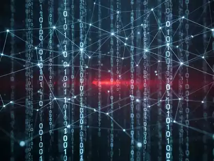 Ein abstraktes Bild, das ein blau leuchtendes digitales Netzwerk und herabfließenden Binärcode vor einem dunklen Hintergrund zeigt, mit einem roten Licht in der Ferne. - Foto: über boerse-global.de