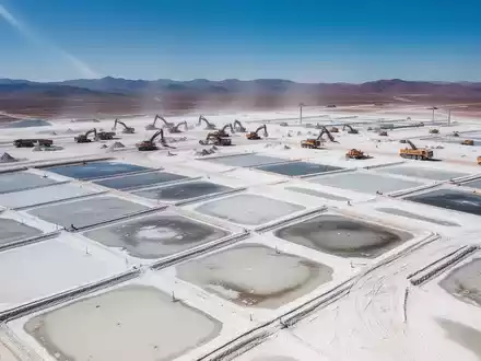 Luftaufnahme einer Lithium-Mine mit weiten, weißen Salzpfannen und geometrischen Verdunstungsteichen unter klarem Himmel. - Foto: über boerse-global.de