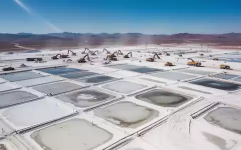 Luftaufnahme einer Lithium-Mine mit weiten, weißen Salzpfannen und geometrischen Verdunstungsteichen unter klarem Himmel. - Foto: über boerse-global.de
