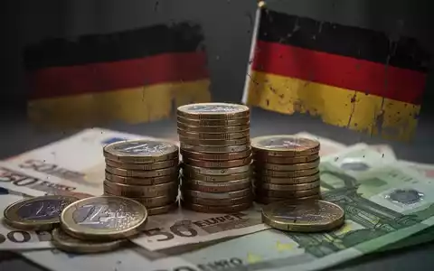 Gestapelte Euro-Münzen und -Banknoten mit einer dezenten, leicht unscharfen deutschen Flagge im Hintergrund, die finanzielle Not symbolisieren. - Foto: über boerse-global.de