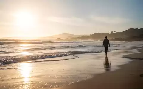 Eine ruhige, sonnenverwöhnte Küstenlandschaft mit sanften Wellen und einer Person, die am Strand entlanggeht, symbolisiert Linderung von Schmerzen. - Foto: über boerse-global.de