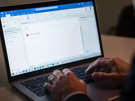 Nahaufnahme einer MacBook-Tastatur und eines Bildschirms mit der Microsoft Outlook-Anwendung, die eine Fehlermeldung oder leere E-Mail-Antwort anzeigt. - Foto: über boerse-global.de