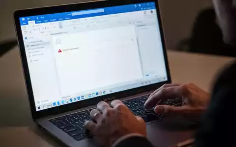 Nahaufnahme einer MacBook-Tastatur und eines Bildschirms mit der Microsoft Outlook-Anwendung, die eine Fehlermeldung oder leere E-Mail-Antwort anzeigt. - Foto: über boerse-global.de