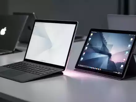 Microsoft Surface Pro-Tablet und Surface Laptop auf einem Schreibtisch, die neue, günstigere Modelle repräsentieren. Ein verschwommener Konkurrenz-Laptop im Hintergrund. - Foto: über boerse-global.de