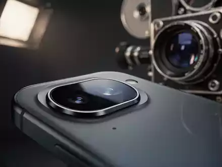 Nahaufnahme einer modernen Smartphone-Kamera, die Studiolichter reflektiert, mit unscharfer Vintage-Kino-Kamera im Hintergrund. - Foto: über boerse-global.de