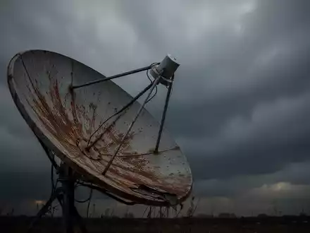Eine leicht verrostete Satellitenschüssel zeigt in einen dunklen, bewölkten Himmel, der einen Rückgang symbolisiert. - Foto: über boerse-global.de