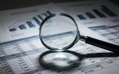 Eine Nahaufnahme eines Vergrößerungsglases über einem Finanzbericht, mit unscharfen Diagrammen und Grafiken im Hintergrund. - Foto: über boerse-global.de