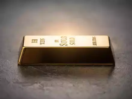 Ein glänzender Goldbarren auf einer dunklen Oberfläche, von hinten beleuchtet, um seinen Glanz hervorzuheben. - Foto: über boerse-global.de