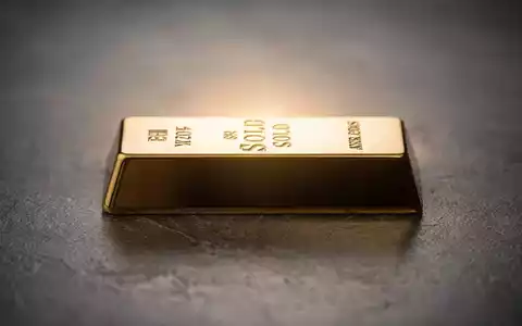 Ein glänzender Goldbarren auf einer dunklen Oberfläche, von hinten beleuchtet, um seinen Glanz hervorzuheben. - Foto: über boerse-global.de