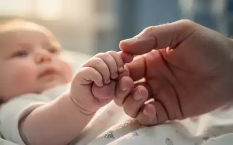 Eine kleine Babyhand greift sanft nach dem Finger eines Erwachsenen, symbolisiert Fürsorge und gesunde Ernährung. - Foto: über boerse-global.de