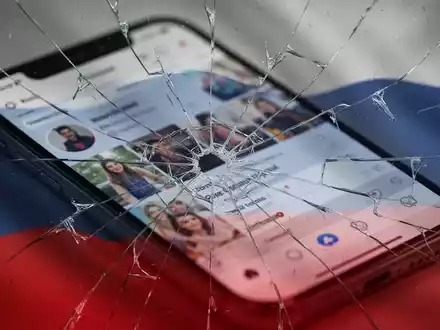 Zerbrochener Smartphone-Bildschirm mit verschwommener Social-Media-App, dezent überlagert von einer beschädigten russischen Flagge. - Foto: über boerse-global.de