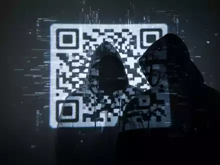 Eine schattenhafte Figur mit Kapuzenpullover vor einem digital verzerrten, leuchtenden QR-Code, der eine Bedrohung symbolisiert. - Foto: über boerse-global.de