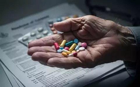 Eine Nahaufnahme der Hand einer älteren Person, die verschiedene Pillen hält, mit verschwommenen medizinischen Dokumenten im Hintergrund. - Foto: über boerse-global.de