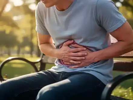Eine Person sitzt auf einer Parkbank und hält sich den Bauch, um Unwohlsein im Sommer darzustellen. - Foto: über boerse-global.de