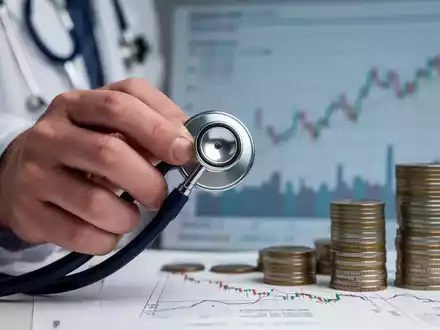 Eine Hand im Arztkittel hält ein Stethoskop, im Hintergrund verschwommene Finanzgrafiken, die finanzielle Belastung im Gesundheitswesen darstellen. - Foto: über boerse-global.de