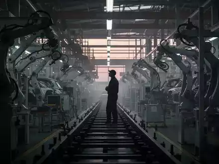 Eine nachdenkliche Silhouette eines Arbeiters in einer dunklen Autofabrik, die Unsicherheit und Arbeitsplatzkrise bei VW andeutet. - Foto: über boerse-global.de