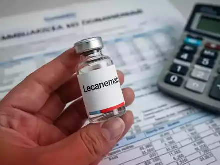 Eine Hand hält ein Medikamentenfläschchen, unscharf im Hintergrund sind italienische Finanzdokumente und ein Taschenrechner zu sehen. - Foto: über boerse-global.de