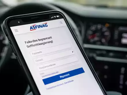 Nahaufnahme eines Smartphone-Bildschirms mit einer gefälschten ASFINAG-Website und einem Zahlungsformular auf einem Armaturenbrett. - Foto: über boerse-global.de