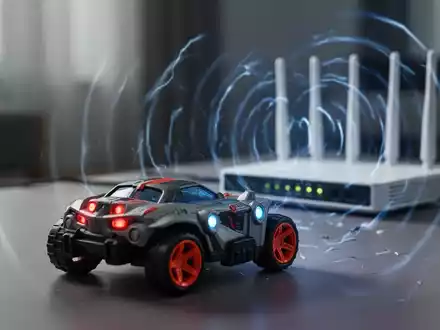Ein Spielzeug-Funkauto im Vordergrund, unscharf, mit einem unscharfen WLAN-Router im Hintergrund, der Störungen aussendet. - Foto: über boerse-global.de