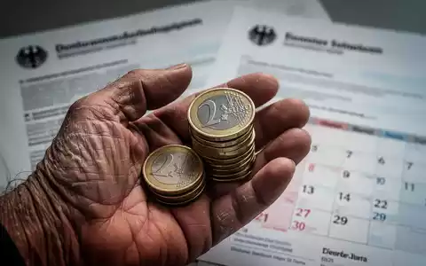 Eine Nahaufnahme einer gealterten Hand, die Euro-Münzen hält, mit unscharfen deutschen Regierungsdokumenten im Hintergrund, die Rentenreformen symbolisieren. - Foto: über boerse-global.de