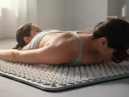 Eine Person liegt mit dem Rücken auf einer modernen Akupressurmatte mit vielen kleinen Spitzen, um Entspannung zu finden. - Foto: über boerse-global.de
