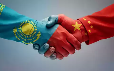 Eine stilisierte Grafik eines Händedrucks, gebildet aus den Flaggen Kasachstans und Chinas, die ein Handelsvolumen von 100 Milliarden symbolisiert. - Foto: über boerse-global.de