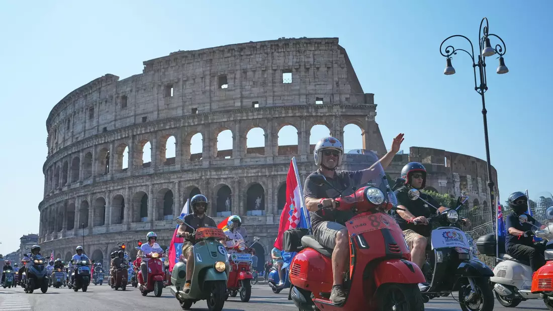 Vespa-Fans fahren am Kolosseum vorbei. - Bild: Alessandra Tarantino/AP/dpa