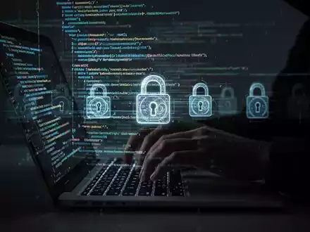 Schattenhafte Hände tippen auf Laptop mit leuchtendem Code und digitalen Schlössern, Symbol für Cyberbedrohungen und Prävention. - Foto: über boerse-global.de