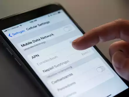 Nahaufnahme eines iPhone-Bildschirms mit Mobilfunkeinstellungen, Finger kurz vor dem Tippen. Anzeige von 'Mobiles Datennetz' und APN-Feldern. - Foto: über boerse-global.de