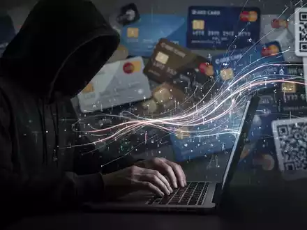 Eine Person im Kapuzenpulli tippt auf einem Laptop, umgeben von digitalen Datenströmen und unscharfen Kreditkarten/QR-Codes. - Foto: über boerse-global.de
