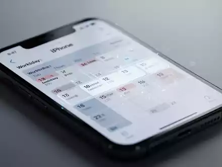 Nahaufnahme eines iPhone-Bildschirms mit Kalender-App und markierten Arbeitstagen, die erweiterte Planungsfunktionen zeigt. - Foto: über boerse-global.de