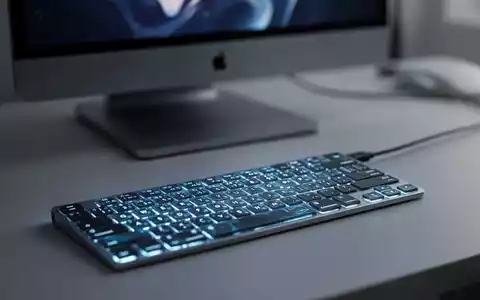 Moderne, hintergrundbeleuchtete Tastatur auf einem Schreibtisch vor einem verschwommenen Apple MacBook, das Mac-Peripherietechnologie zeigt. - Foto: über boerse-global.de