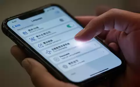 Nahaufnahme einer Hand, die auf einem iPhone-Sprach- oder NLP-Einstellungen bedient. - Foto: über boerse-global.de