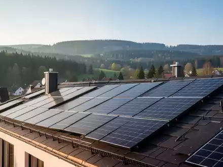 Solarmodule auf einem Hausdach in Deggendorf, mit Blick auf die Stadt und den Bayerischen Wald bei strahlendem Sonnenschein. - Foto: über boerse-global.de