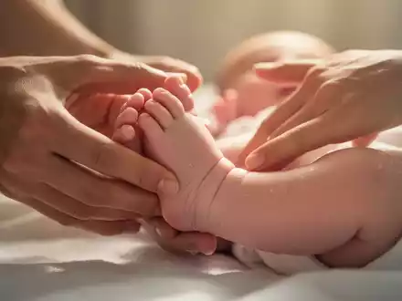 Nahaufnahme der Füße eines Babys, das sanft von Erwachsenenhänden massiert wird, in einer warmen, beruhigenden Umgebung. - Foto: über boerse-global.de