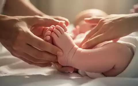 Nahaufnahme der Füße eines Babys, das sanft von Erwachsenenhänden massiert wird, in einer warmen, beruhigenden Umgebung. - Foto: über boerse-global.de
