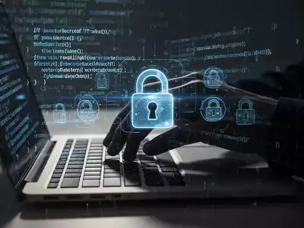 Schattenhafte Hand tippt auf Laptop-Tastatur, digitale Vorhängeschloss-Symbole überlagert, symbolisiert Cybersicherheitsbedrohungen. - Foto: über boerse-global.de