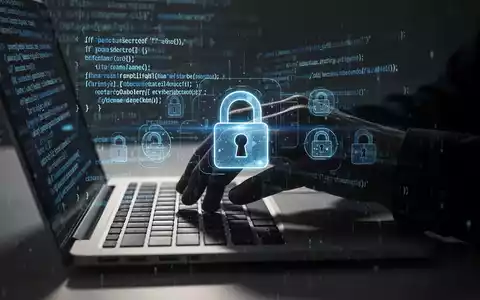 Schattenhafte Hand tippt auf Laptop-Tastatur, digitale Vorhängeschloss-Symbole überlagert, symbolisiert Cybersicherheitsbedrohungen. - Foto: über boerse-global.de