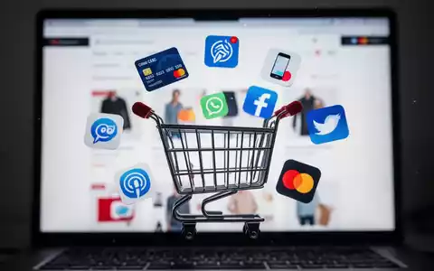 Ein stilisiertes Einkaufswagensymbol umgeben von digitalen Zahlungssymbolen vor einem verschwommenen Bildschirm einer E-Commerce-Website. - Foto: über boerse-global.de