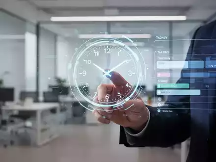 Eine Hand interagiert mit einer holografischen Uhr oder einem Zeitplan, der eine optimierte Arbeitsroutine in einem modernen Büro symbolisiert. - Foto: über boerse-global.de