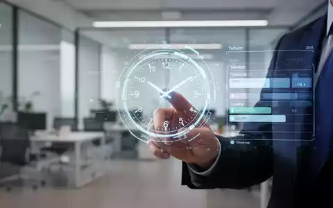 Eine Hand interagiert mit einer holografischen Uhr oder einem Zeitplan, der eine optimierte Arbeitsroutine in einem modernen Büro symbolisiert. - Foto: über boerse-global.de